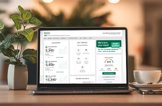 Computer displaying updated Bank of Washington digital banking homepage with coffee cup and plant