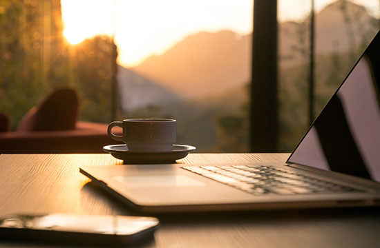 open laptop with coffee mug and mobile phone on desk nearby